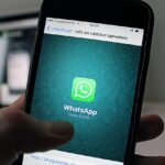 Immagine di un telefono con l'app WhatsApp aperta, con messaggi evidenziati e un'icona di intelligenza artificiale.
